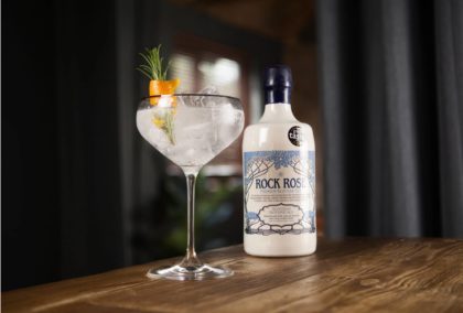 Rock Rose Gin Original Edition and perfect serve in a coupe glass garnished orange peel and sprig of thyme