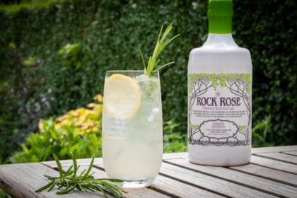 Bottle of Rock Rose Gin Spring Edition and Elderflower & Herb Gin Fizz Cocktail served on a tall glass and garnished with slice of lemon and thyme sprig