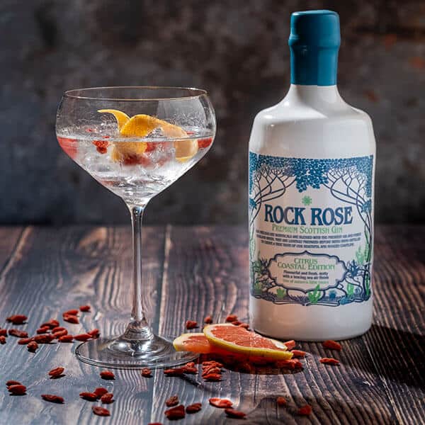 Bottle of Rock Rose Gin Coastal Edition and perfect serve in a coupe glass garnished with a slice of grapefruit