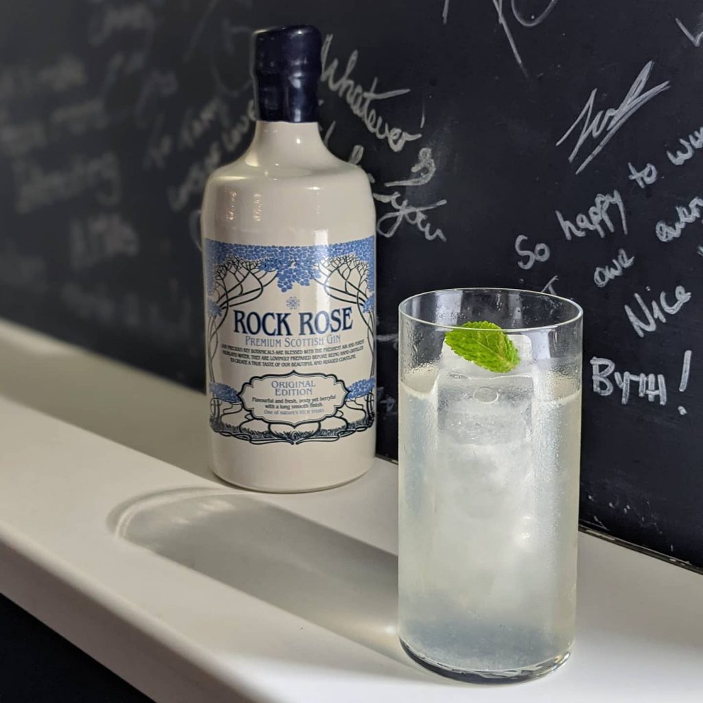 Bottle of Rock Rose Gin with The North Coast Southside cocktail - by Max Hayward - served in a long glass and garnished with a mint leaf