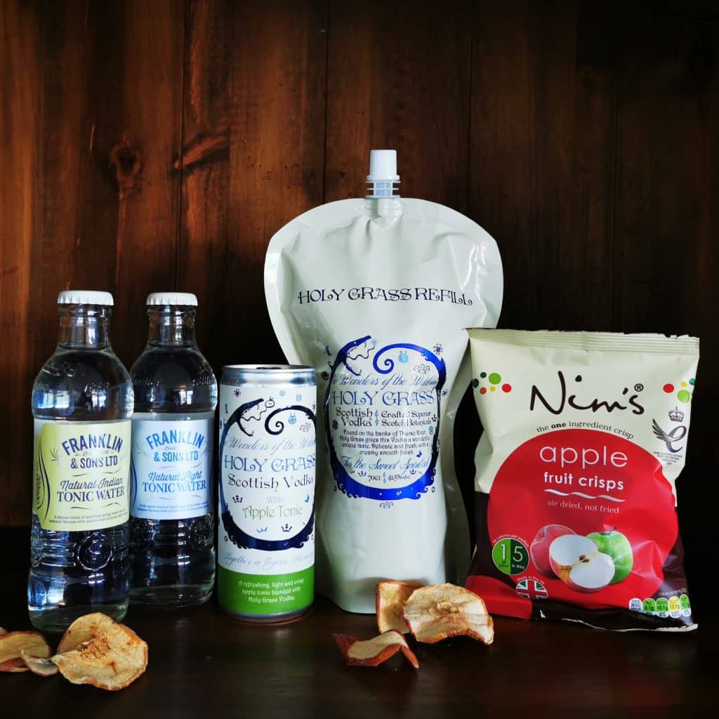 Content of the Refill Rewards Club box for May 2022 including Holy Grass Vodka pouch with tonic waters, holy grass vodka with apple tonic can, apple fruit crisps