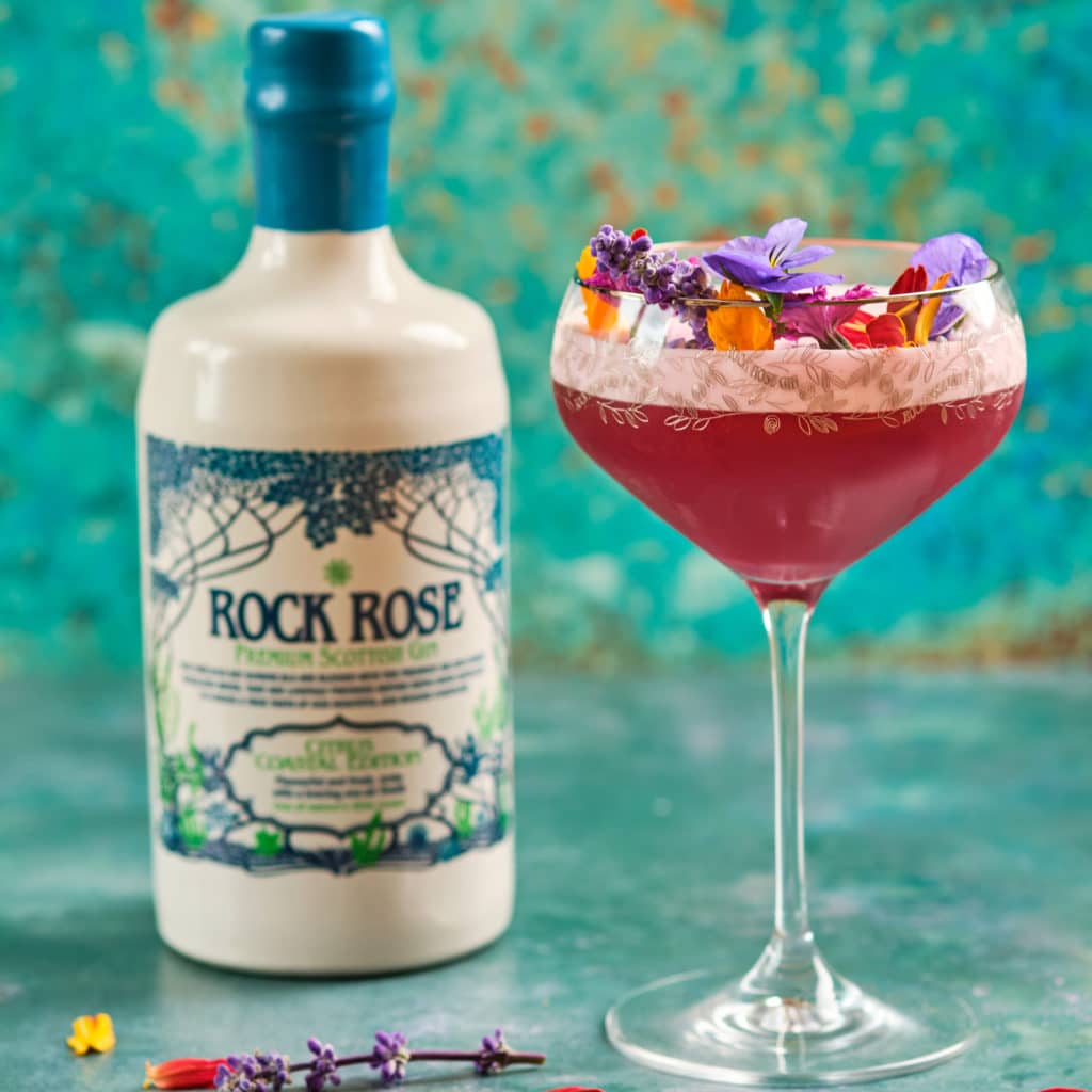 Bottle of Rock Rose Gin Citrus Coastal Edition and Caithness Garden cocktail served in a coup glass and garnish with edible flowers