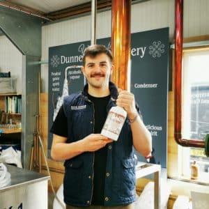 Craig holding a bottle of Rock Rose Gin Smoked Orange in the still house