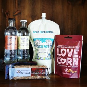 Content of the Refill Rewards Club box for August 2022 including Rock Rose Citrus Coastal edition pouch, tonic waters, Scottish Macarron, smoked barbecue corn