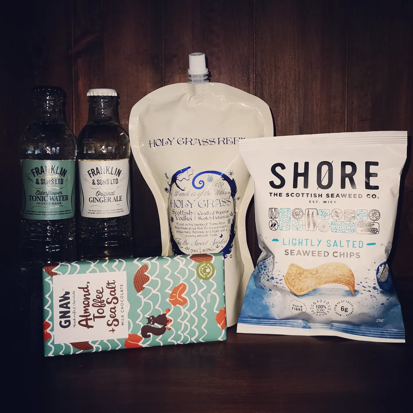 Content of the Refill Rewards Club box for September 2022 including Holy Grass Vodka pouch, Shore seaweed crisps, tonic water and ginger ale, and almond toffee and sea salt milk chocolate