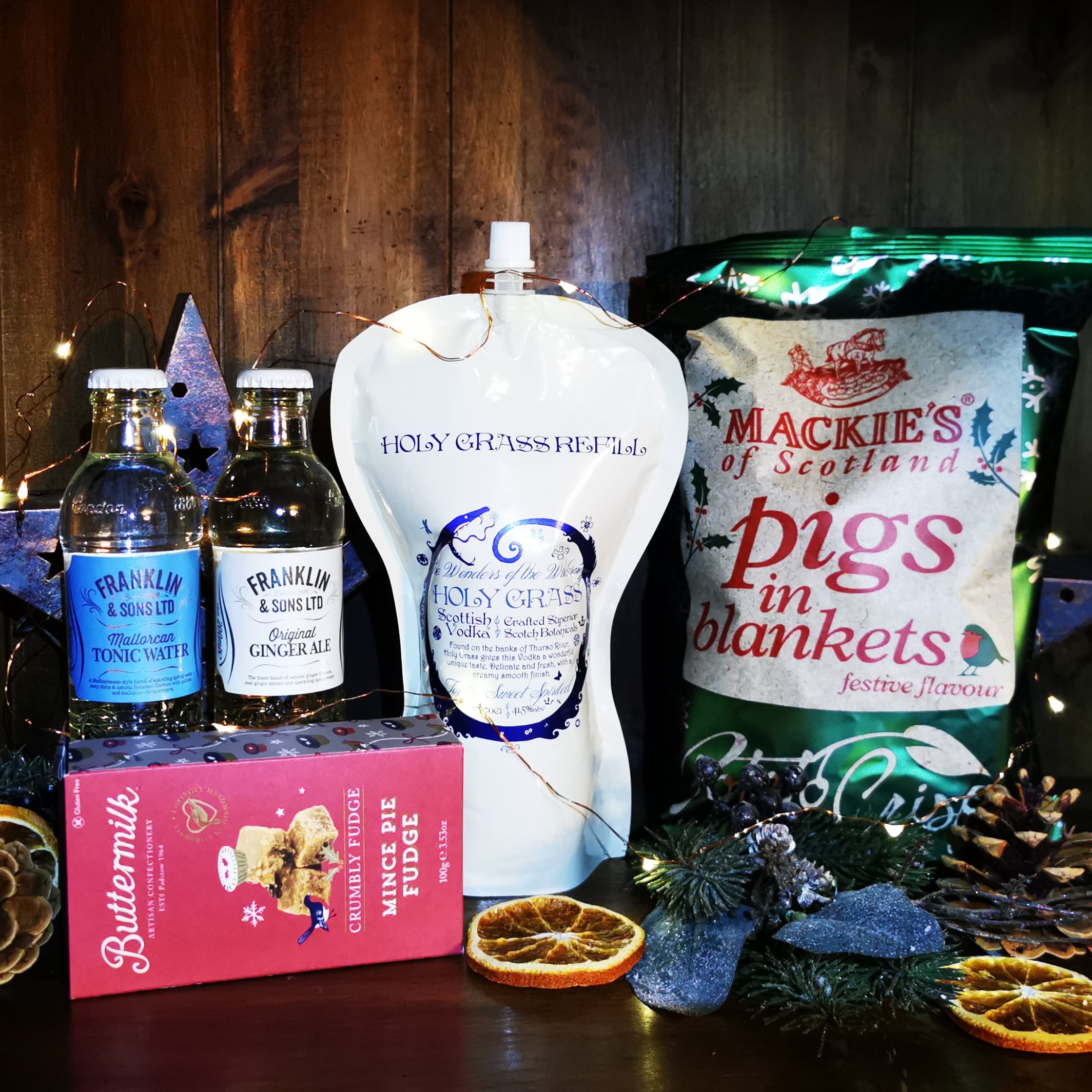 Content of the Refill Rewards Club box for December 2022 including Holy Grass Vodka pouch, tonic water, ginger ale, mince fudge, pigs in blankets crisps