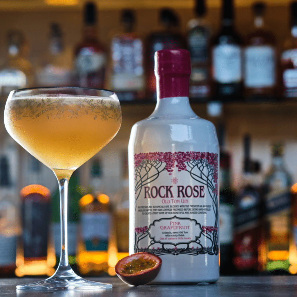 Bottle of Rock Rose Gin Old Tom edition with Passion Fruit Sour cocktail served in a branded coupe glass.